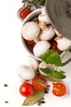 top view on white mushrooms in pan, sliced cherry tomatoes, garlic and herbs over white  の写真素材