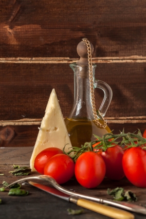 wet red cherry tomatoes and cheese parmesan on wooden table with olive oil in vintage glass bottle の写真素材