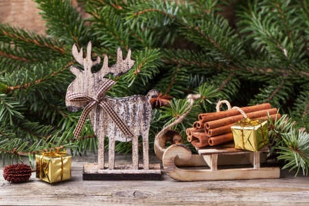 Christmas card with wooden deer, sled, cinnamon and christmas gifts over old wooden backgroundの写真素材