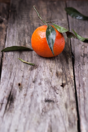 One tangerine with leaves on old wooden の写真素材