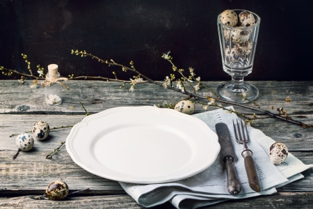 Easter table setting with vintage silverware, white plate, gray textile napkin, quail eggs and...