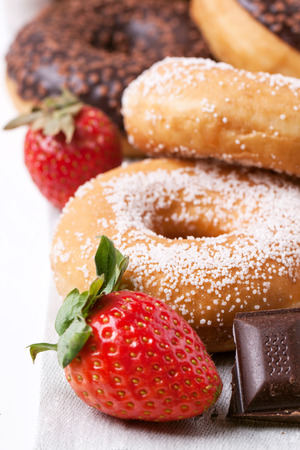 Close up of sugar donuts, fresh strawberries and dark chocolate over whiteの写真素材