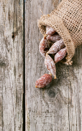 Top view on sak with little salami over old wooden table. See series.の写真素材