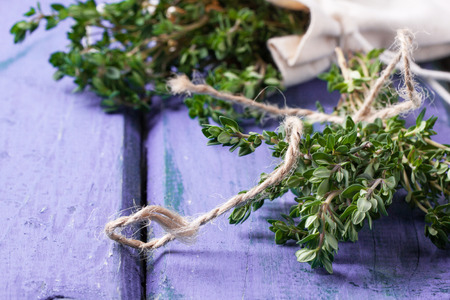 Bunch of fresh thyme on violet wooden tableの写真素材