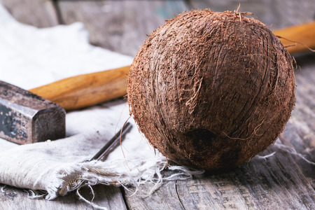 Whole coconut with hammer and nail over old wooden tableの写真素材