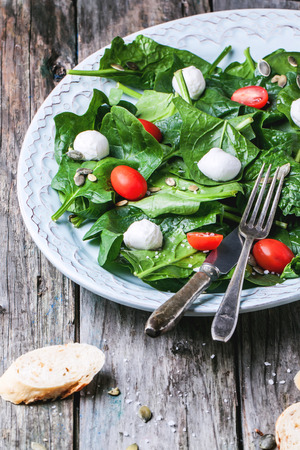 Plate of salad from fresh spinach, tomatoes and mozzarella with bread. Diet concept.の写真素材