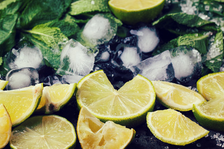 Ingredients for mojito (fresh mint, limes, ice, sugar) over black in retro filter effect.の写真素材