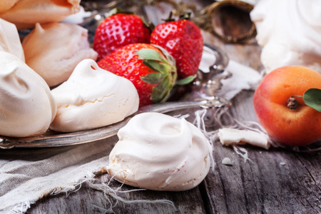 Close up of homemade meringue, served with apricots over wooden table.の写真素材