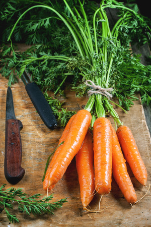 Bunch of fresh carrot with vintage knife on old cutting board.の写真素材