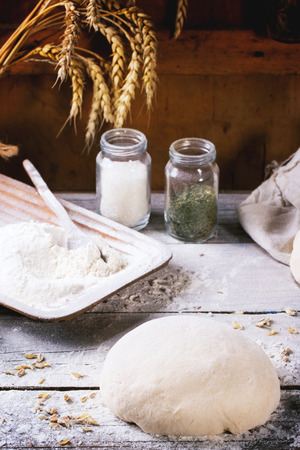 Baking bread. Dough on wooden table with flour, rolling-pin and jars with backing ingredients.の写真素材