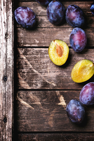 Whole and sliced plums over old wooden table. Top view.の写真素材