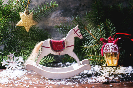 Christmas card with white rocking horse with Christmas tree, toys and snow.の写真素材