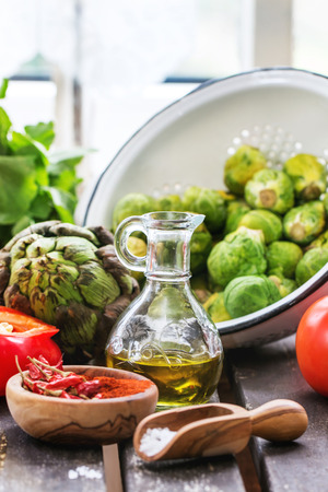 Variation of fresh vegetables tomatoes, pepper, paprika, artichoke and Brussels sprouts on old table near window in day light.の写真素材