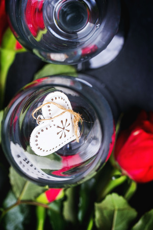 St Valentine greeting card with two champagne glasses with red roses and heart at black stone background. Top view. See seriesの写真素材