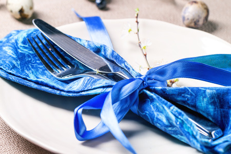 Easter table setting with blue textile napkin, blossom branch and quail eggsの写真素材