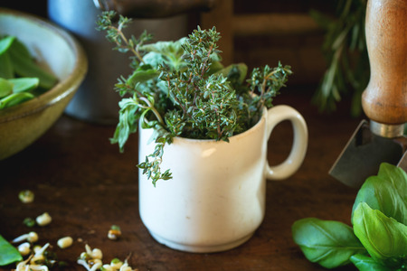 Young sweet peas and mix of herbs rosemary and basil with vintage kitchen utensil over wooden tableの写真素材