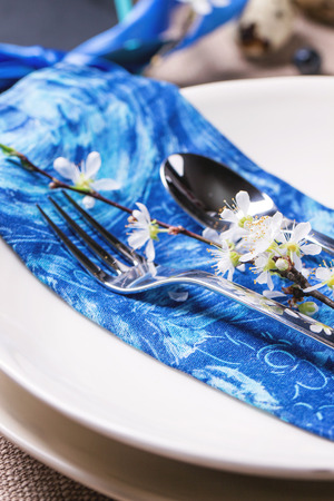 Easter table setting with blue textile napkin and blossom cherry branchの写真素材