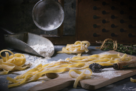 Making homemade pasta linguine on rustic kitchen table with flour, vintage sieve and cutting board. See series.の写真素材