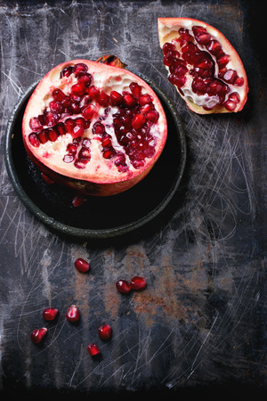 Half of pomegranate with seeds over black metal surface. Top viewの写真素材