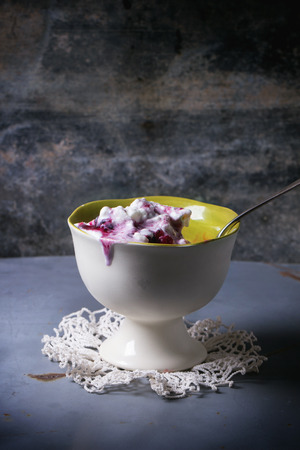 White ceramic vase with vanilla ice cream, served with mix of berries over gray metal tableの写真素材