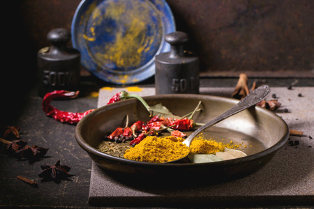 Spices tumeric and dry red hot chili peppers on metal plate, served over dark table with vintage weight and blue ceramic plate.の写真素材