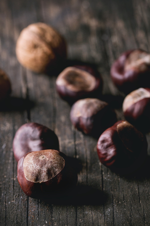 Heap of Uncooked edible chestnuts over old wooden table.の写真素材