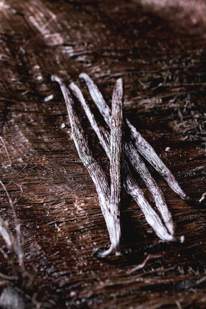 Heap of vanilla sticks over dark palm crust.の写真素材