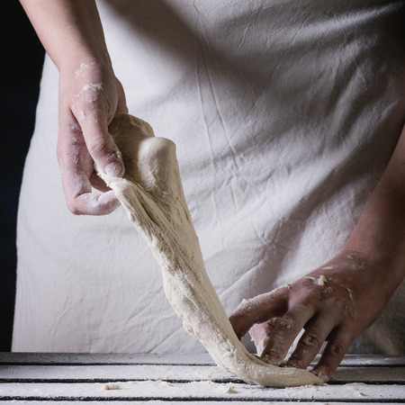Women's hands making the dough for pizza.  Square image with selective focus