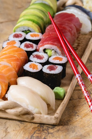 Sushi set nigiri and rolls on clay plate served with chopsticks on stone surface. Flat lay.の写真素材