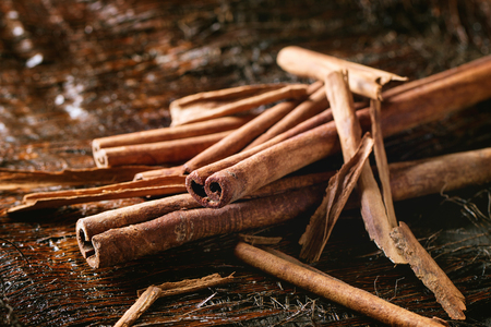 Close up of Heap of different cinnamon sticks over dark palm crust. Selective focusの写真素材