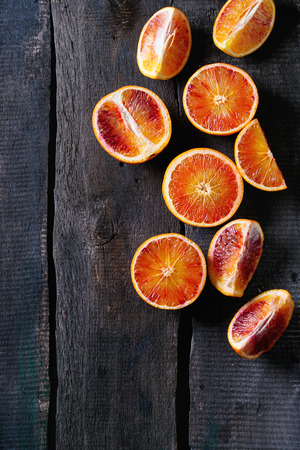 Sliced Sicilian Blood oranges fruits over old dark wooden background. Top viewの写真素材