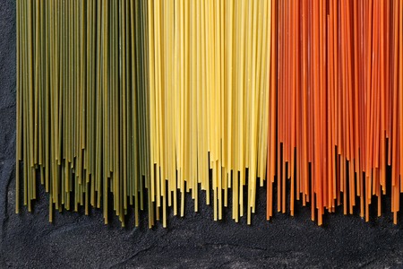Dry colorful pasta spaghetti as italian flag over black textured background. Top viewの写真素材