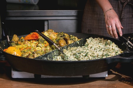 Street food at Prague market. Big iron pan with grilled mushroom and vegetables.