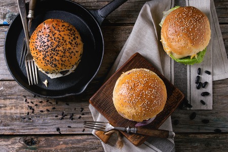 Three Homemade veggie burgers with sweet potato, black rice and red beans, served on wooden chopping board over old wooden table. Rustic style. Flat layの写真素材