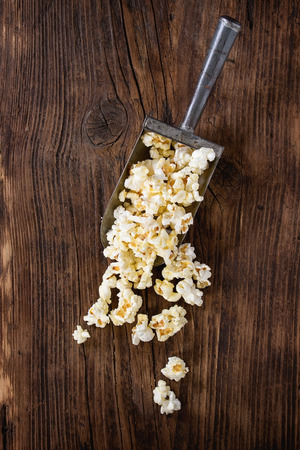 Prepared salted popcorn in old aluminum scoop over dark wooden background. Top view with copy spaceの写真素材