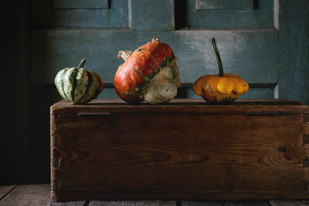 Three decorative pumpkins on wooden chest over wooden background. Dark rustic styleの写真素材