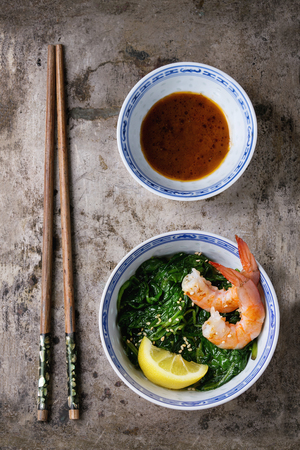 Chinese bowls with Cooked spinach and fried shrimps prawns with lemon and sesame seeds, soy sauce and chopsticks over old iron background. Asian style dinner. Top viewの写真素材