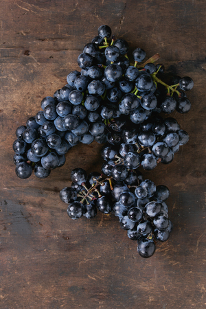 Bunch of ripe wet red grapes over old dark wooden background. Top view with space for textの写真素材