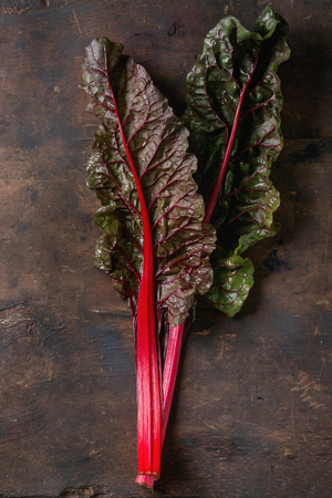 Fresh chard mangold salad leaves over old dark wooden background. Top view with space for text.の写真素材