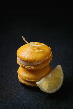 Orange lemon homemade macaroons with white chocolate, lemon slice and zest, and citrus sugar over...