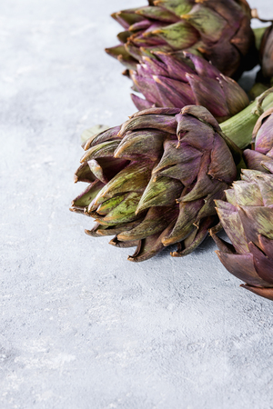 Uncooked whole organic wet purple artichokes over gray texture background. Close upの写真素材