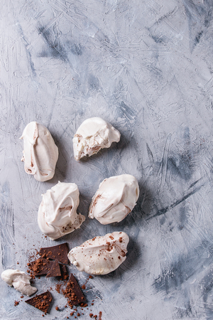 Baking homemade french dessert meringue with chocolate served with dark chopping chocolate and cocoa powder over gray concrete texture background. Top view with copy spaceの写真素材