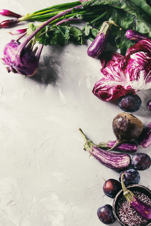 Assortment raw organic of purple vegetables mini eggplants, spring onion, beetroot, radicchio salad, plums, kohlrabi, flower salt over gray concrete background. Top view with space. Food frameの写真素材