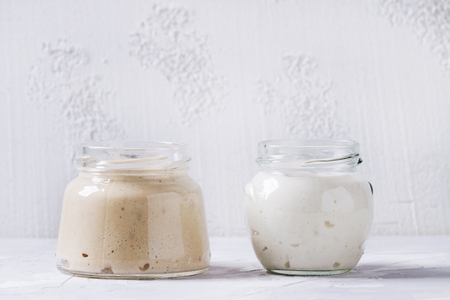Rye and wheat starter sourdough in glass jars for baking homemade bread over gray concrete background.の写真素材
