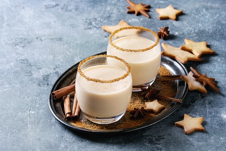 Eggnog Christmas milk cocktail with cinnamon, served in two glasses with shortbread star shape sugar...