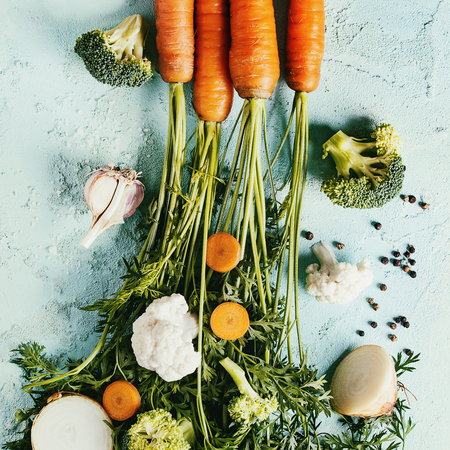 Raw vegetables for cooking soup. Ingredients young carrot with haulm, broccoli, cauliflower, onion, garlic, salt pepper over turquoise concrete background. Top view. Dinner cooking concept. Square imageの写真素材