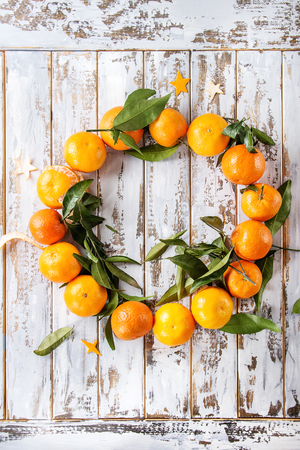 Clementines tangerines with leaves as Christmas wreath over white wooden plank background. Top view, space. New Year cards and decorations.の写真素材