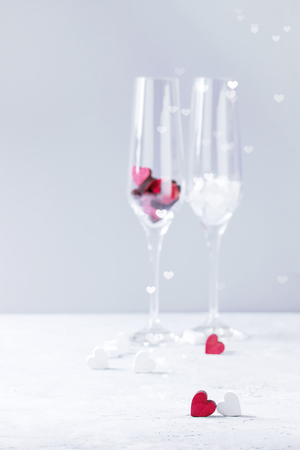 Love Valentine day greeting card with two empty champagne glasses and wooden hearts over white gray background. Copy space. Selective focusの写真素材