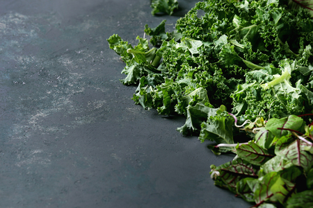 Green salad mix for salad or smoothie with kale, young beetroot leaves, sprouts, over dark texture surface. Copy space. Food background.の写真素材