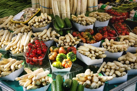 Market stall with fresh spring season vegetables at Parisian street farmers market. White asparagus, tomatoes, cucumbers.の写真素材